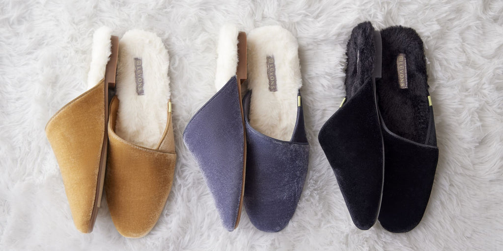 Three pairs of Luvons Devon slippers in camel, slate blue, and black velvet, arranged side by side on a neutral background—chic, cozy, and machine-washable.
